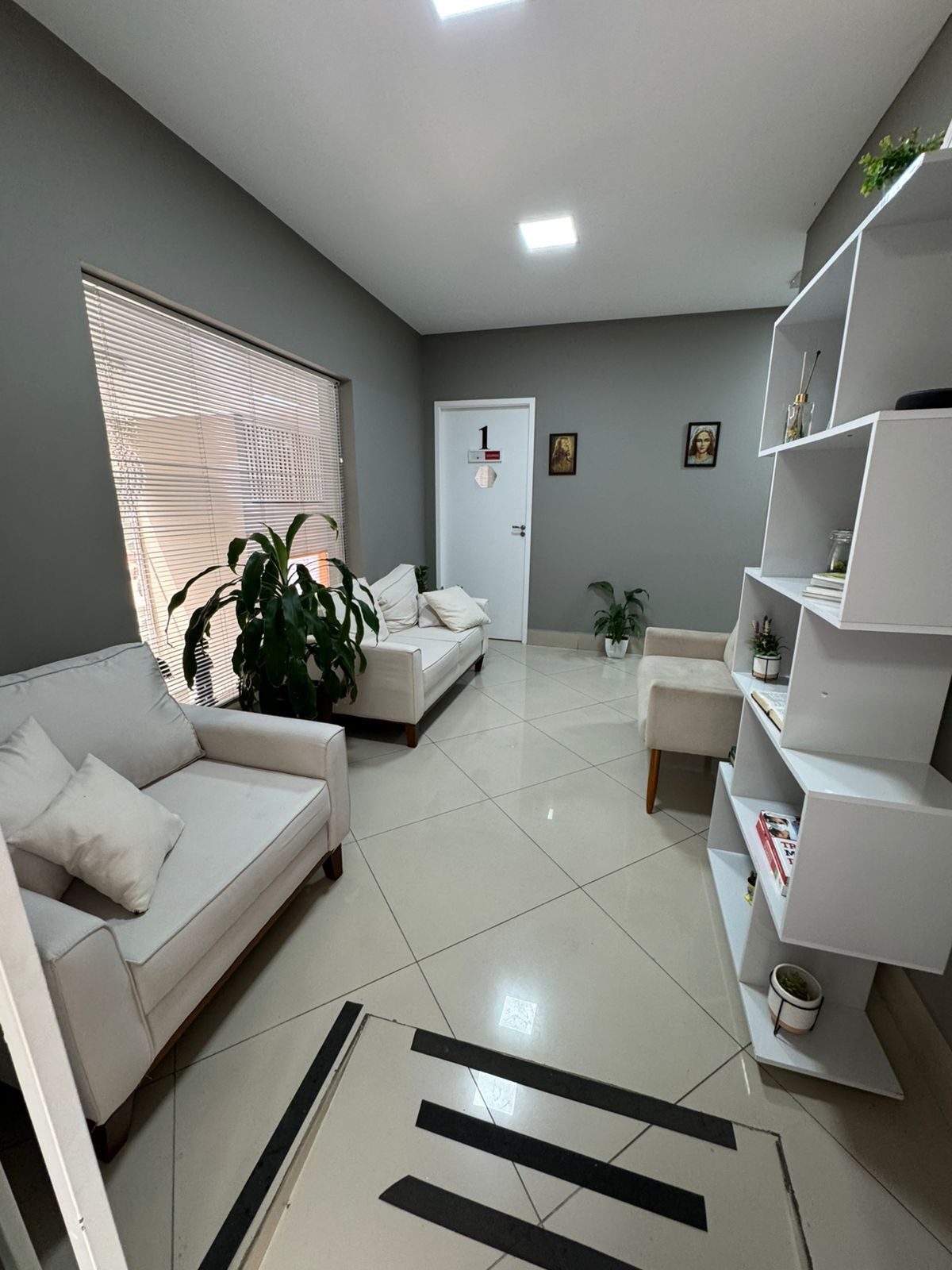 Sala de espera clara com sofás e plantas